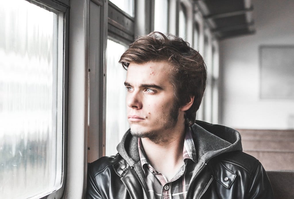 בחור צעיר יושב ברכבת ומביט דרך החלון