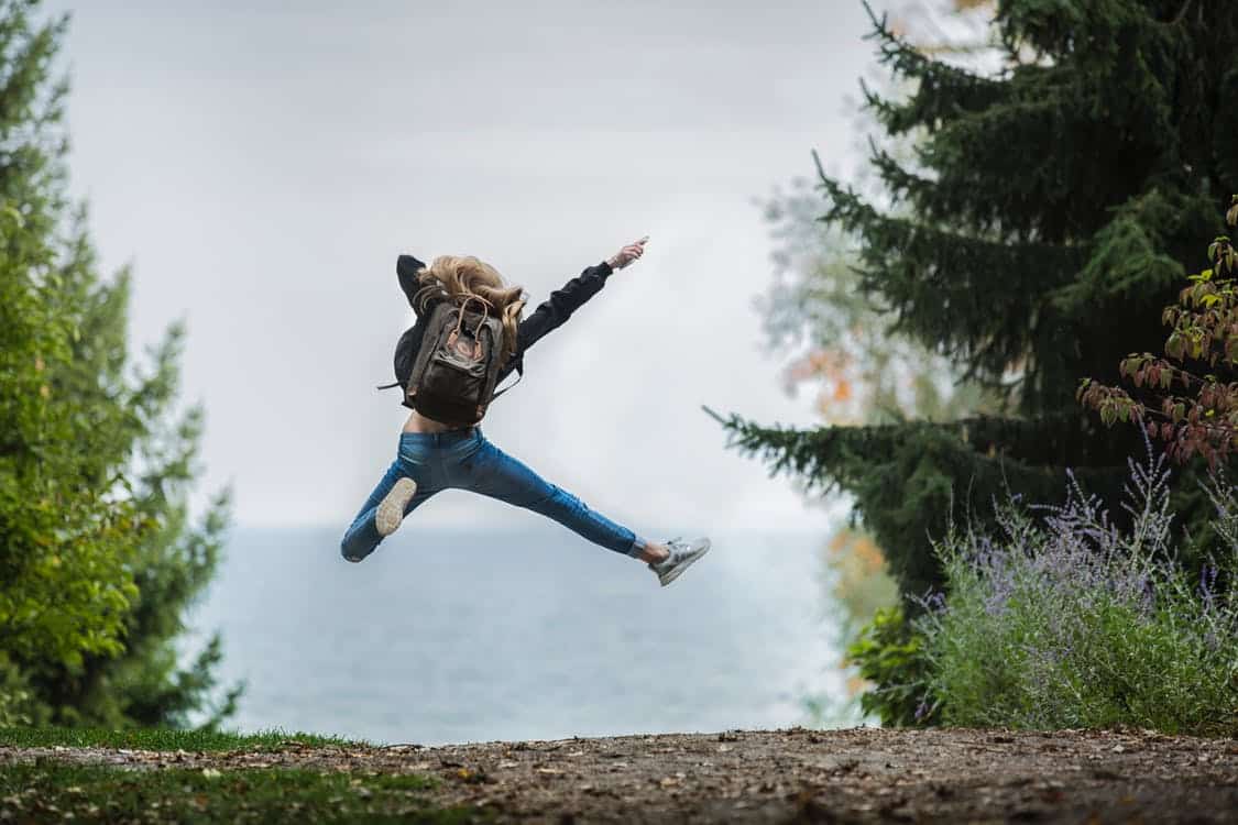 אישה צעירה קופצת מאושר בטבע תמונה אחורית